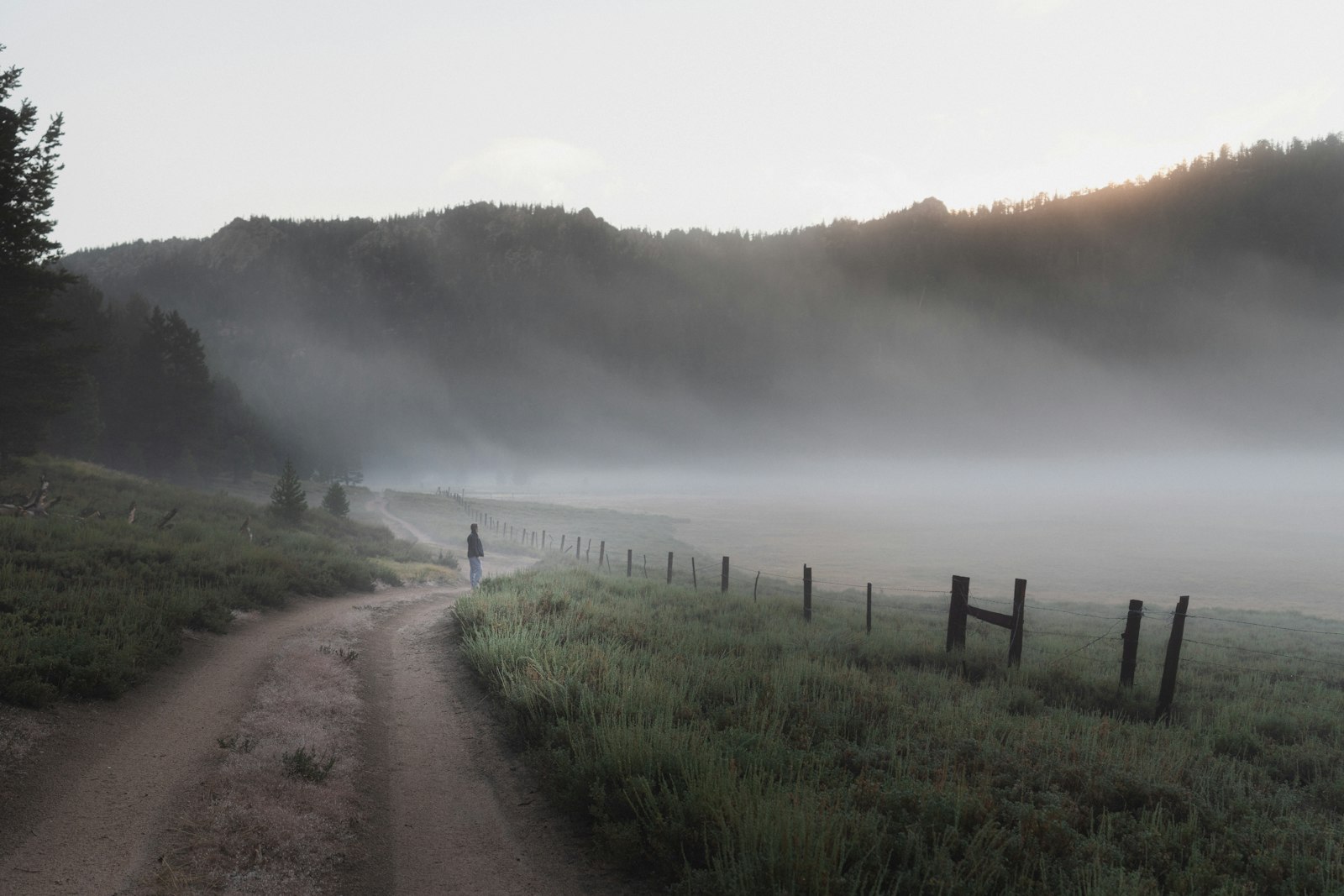 A lone walker on a misty mountain pilgrim path at dawn